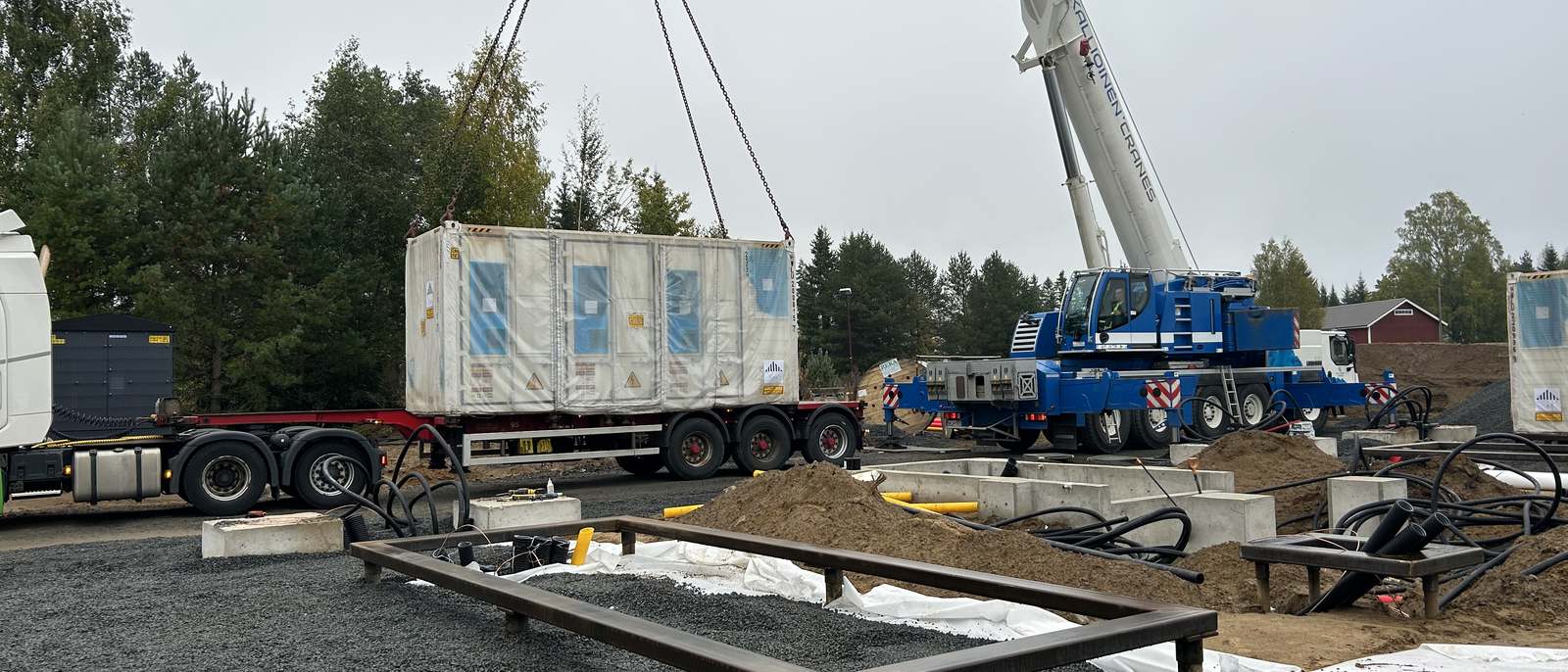 BESS container being lifted by crane onto its helical-pile foundation