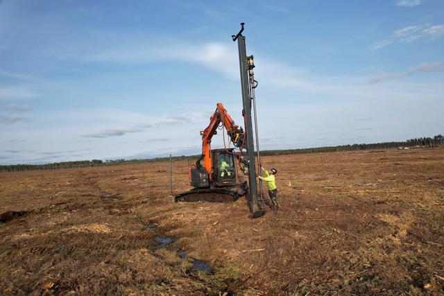 Installation rig and engineer on soft peat ground inspecting site conditions