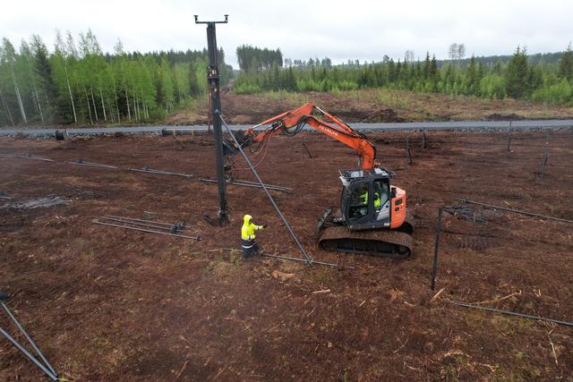 Completed pile field across a cleared site with forest backdrop — the bankable result
